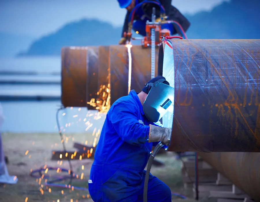 Welder working on a hot rolled carbon steel pipe